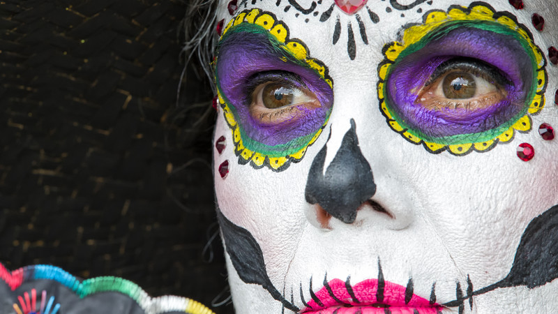A woman in skull face-paint prepares for Day of the Dead celebrations