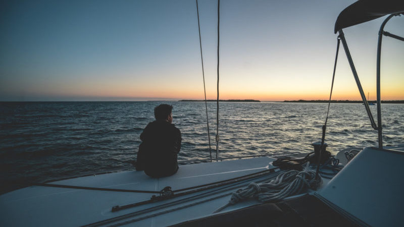 A passenger looks out to sea at sunset