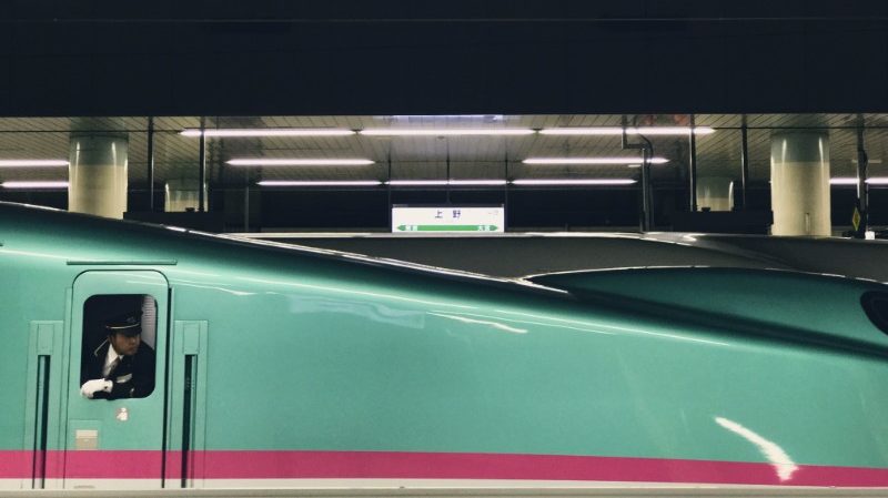 A train driver on a Japanese train leans out the window.
