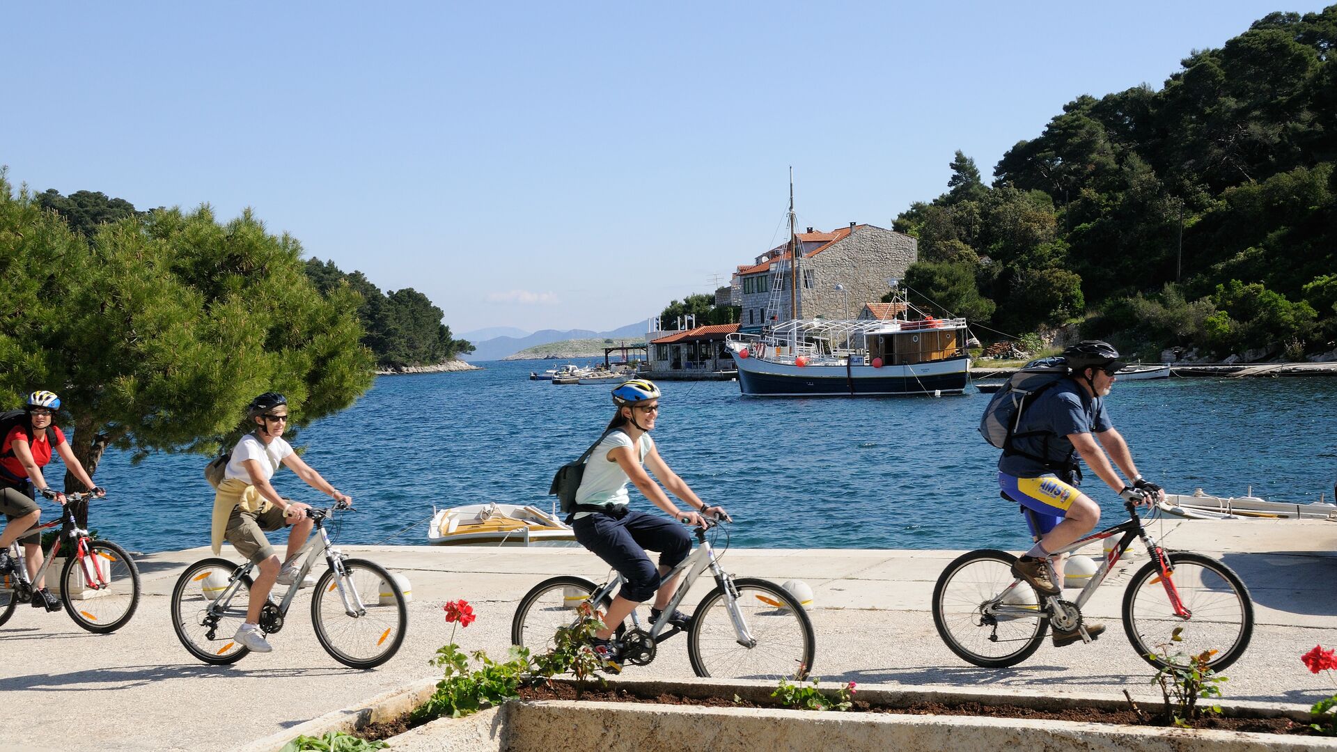 Four travellers cycling on bikes along the water's edge