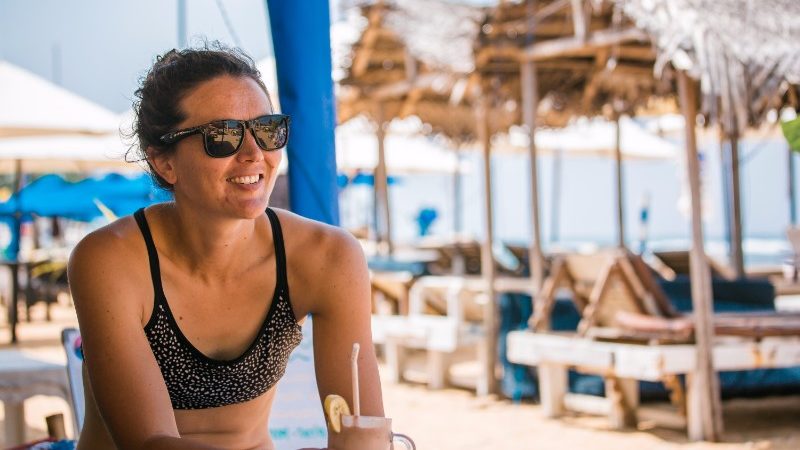 female sitting at beach drinking cocktail