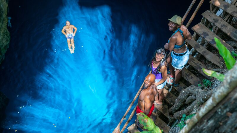 A man floating in a blue cenote in Mexico