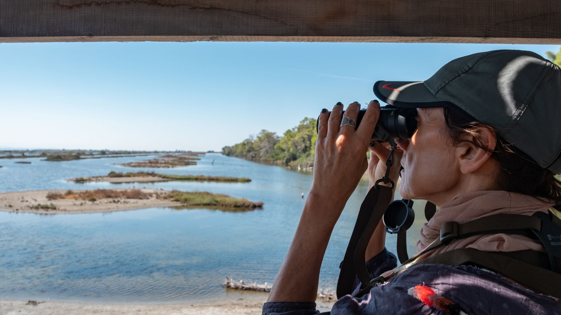 A traveller looking out into the wetlands of Karavasta in Albania with binolculars to spot birds