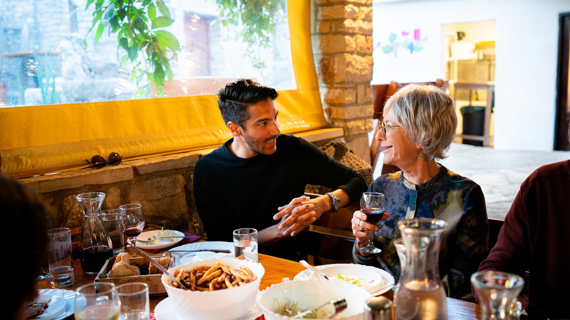 Two travellers talking at the lunch table with wines