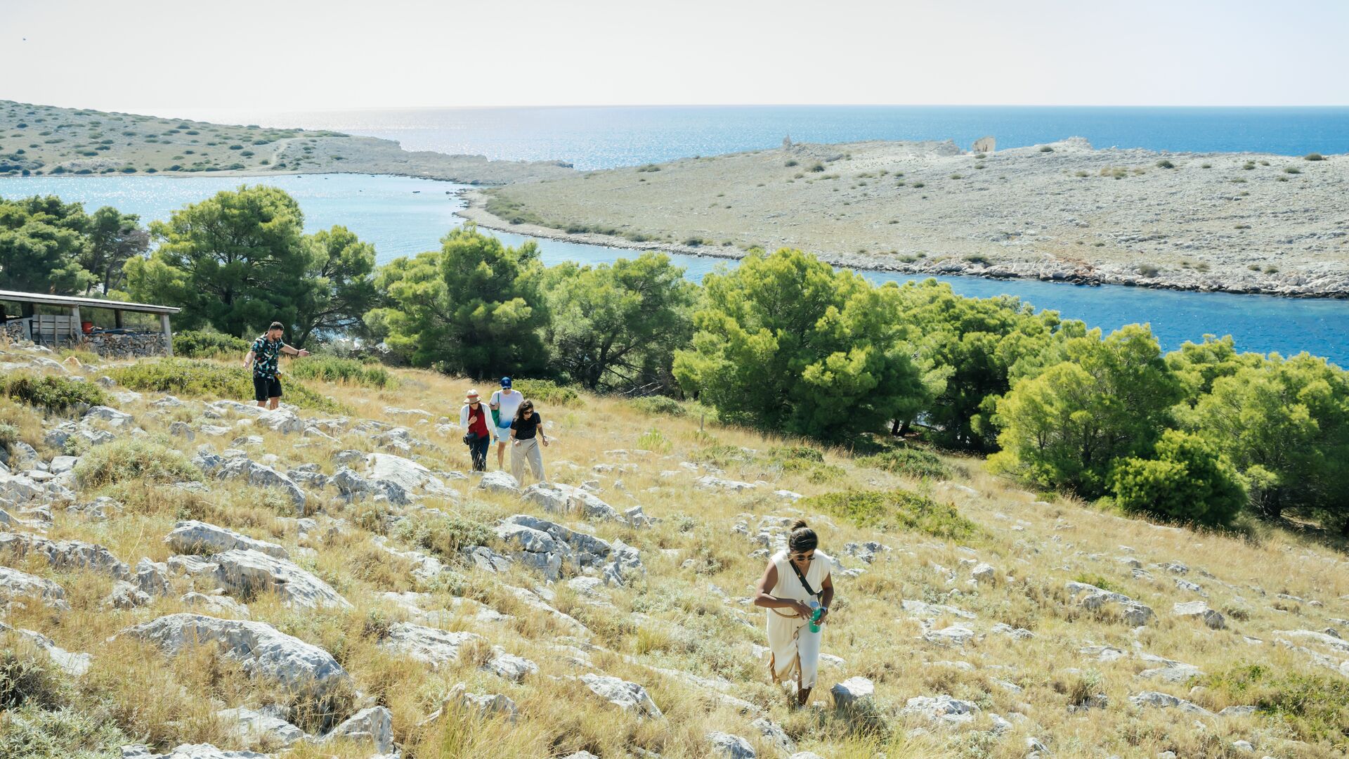 Travellers walk across a hill in Kornati
