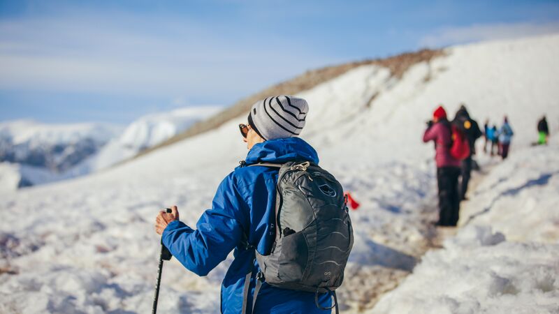 A woman with hiking poles walking through the ice in Antarctica