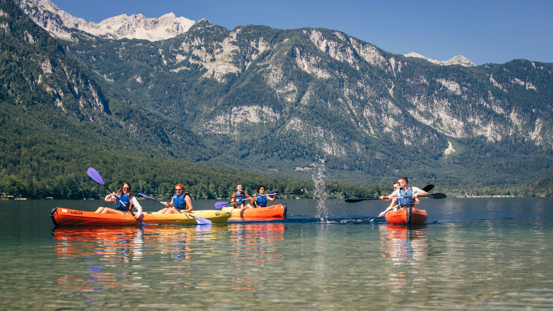 A group of travellers splashing around on a kayaking trip aound Lake Bohinj, Slovenina