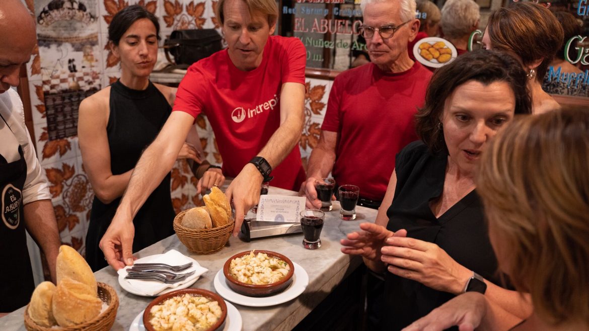 Intrepid leader serves Spanish tapas style food to travellers around a bar