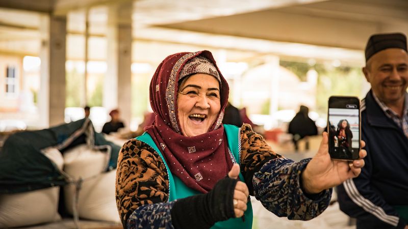 old Uzbek woman with phone laughing