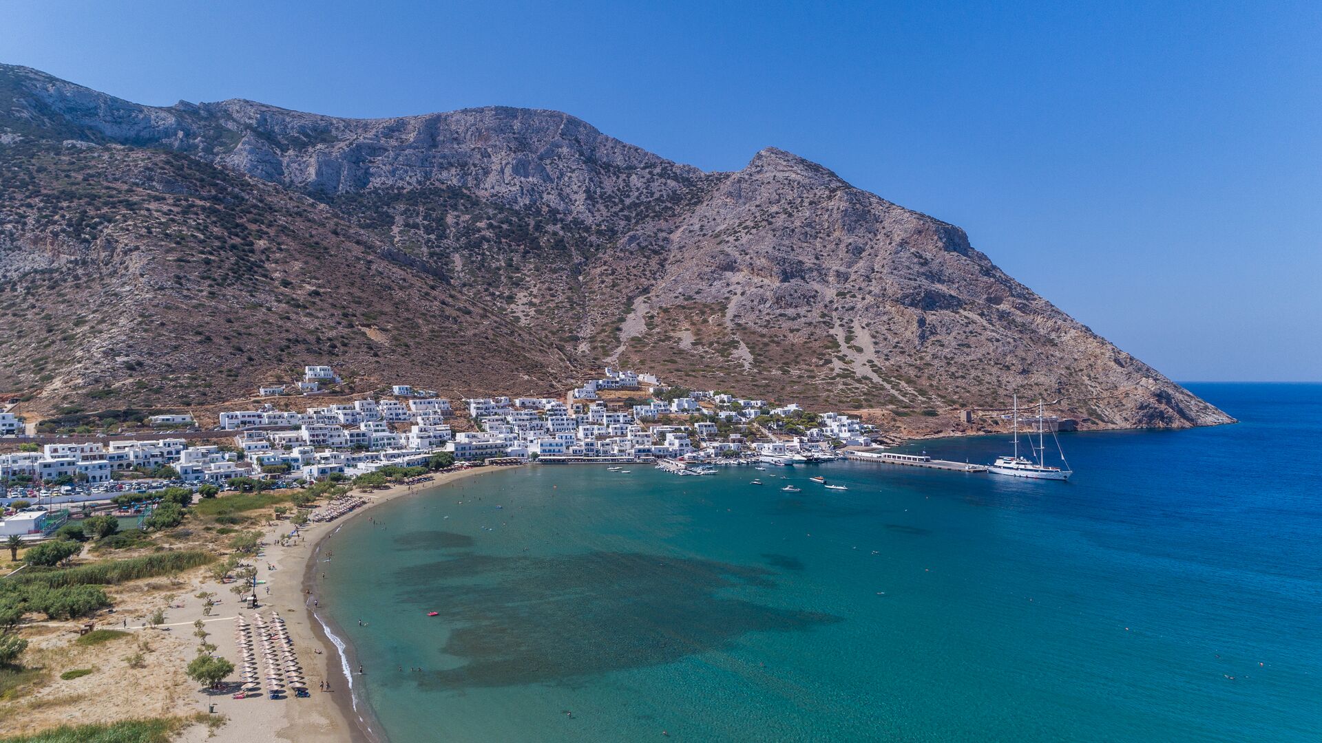A white-washed village at the base of rugged coastal cliffs in Sifnos