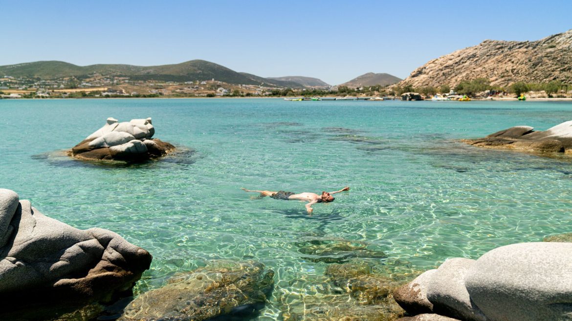 A traveller floating in the crystal-clear waters of Paros, Greece