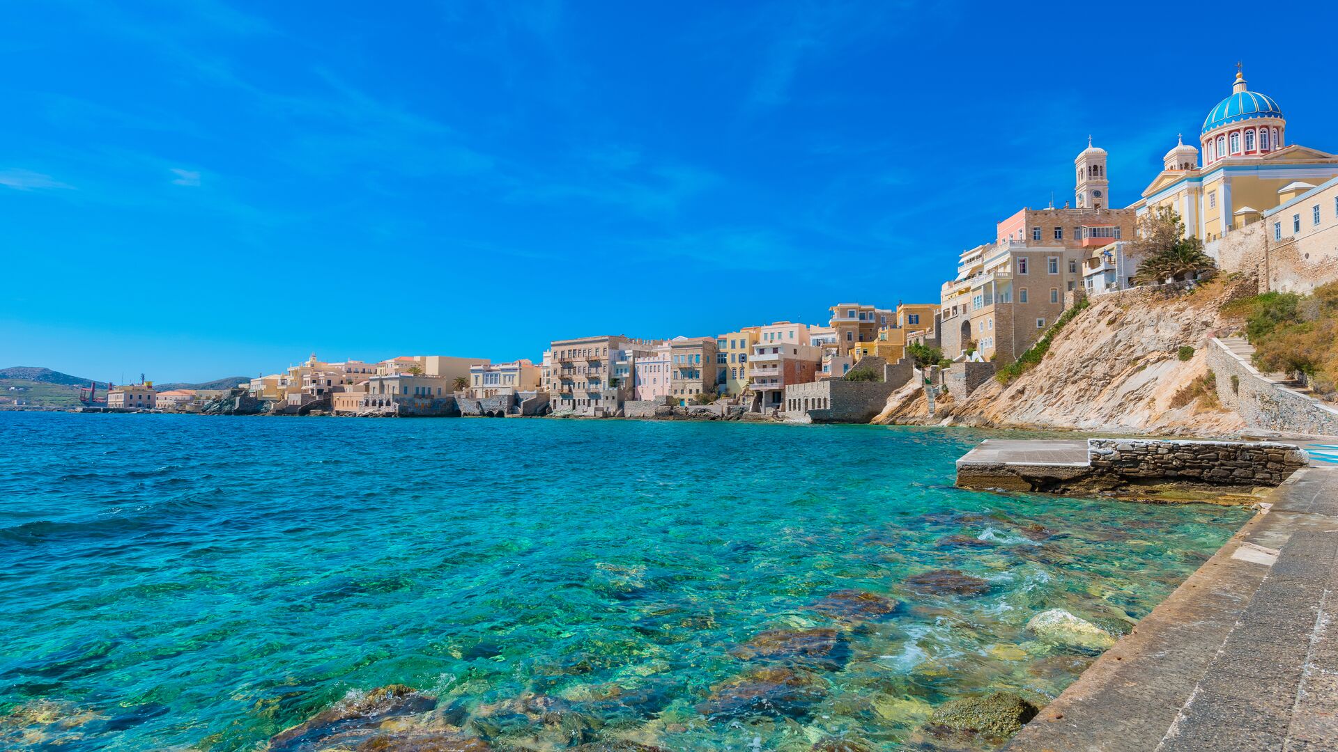 Blue water lapping against concrete sea steps in Syros, Greece