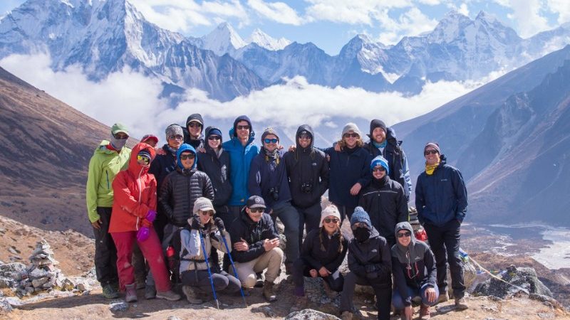 Group of travellers together in front of the snowy peaks of Nepal at a high altitude