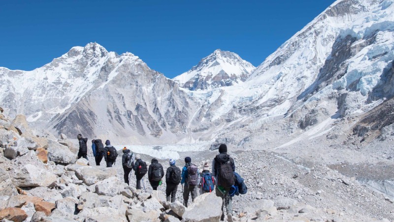 A single line of travellers trek towards the snowy peaks in Nepal