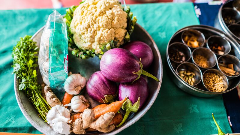 A bowl of vegetables and spices set ontop of a green table cloth