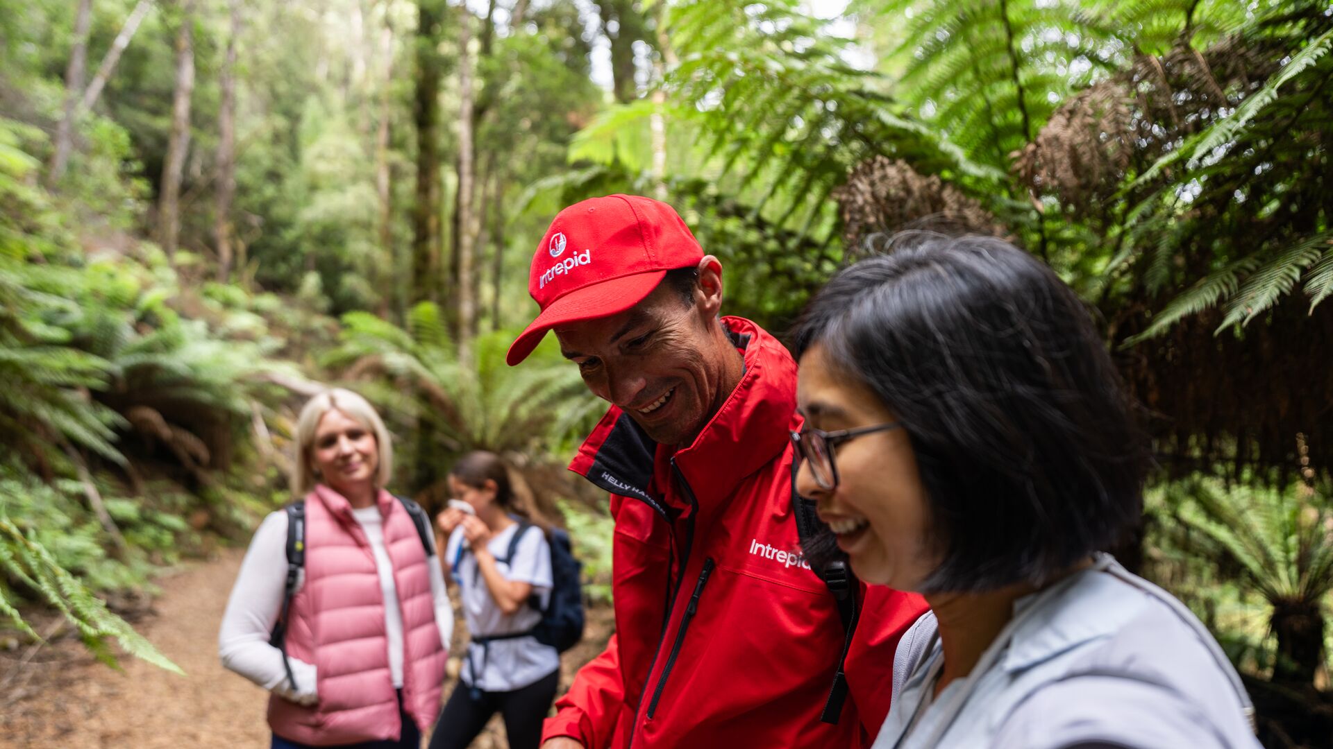 An Intrepid leader talks to a traveller in a rainforest.