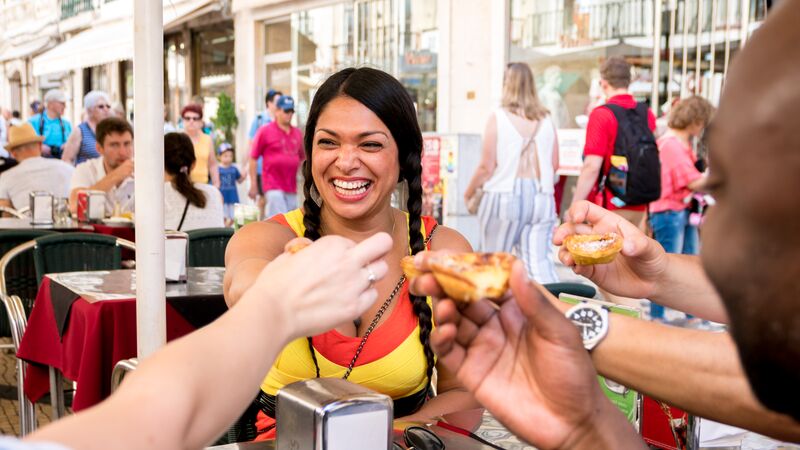 A group of people smiling while eating Portuguese tarts
