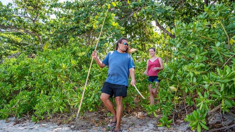 Man and woman walking through bushes to the beach