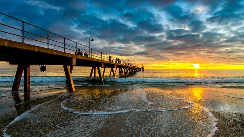 People walking along the jetty at Glenelg Beach at sunset