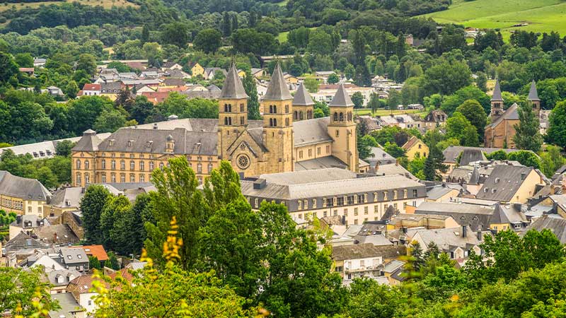 The exquisite exterior of the Abbey of Echternach surrounded by slate-covered roofs of houses in Echternach.