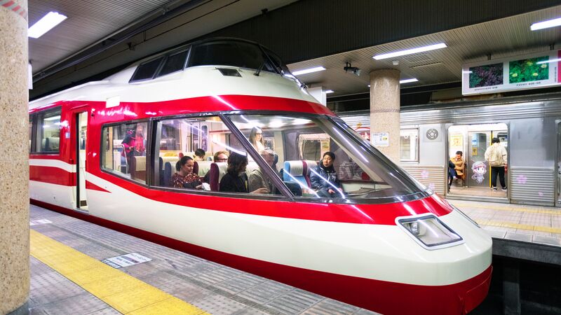 The sleek design of a bullet train with people inside it at a station in Japan.