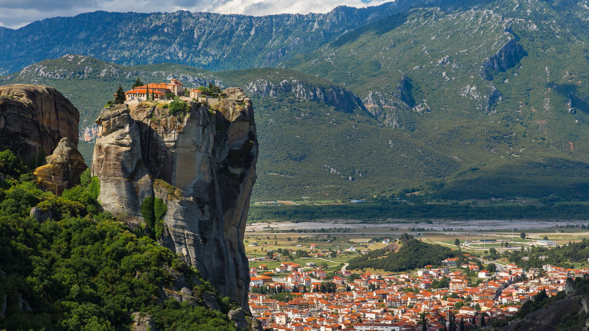 The clifftop monastery of Meteora with the village below and mountains in the distance.