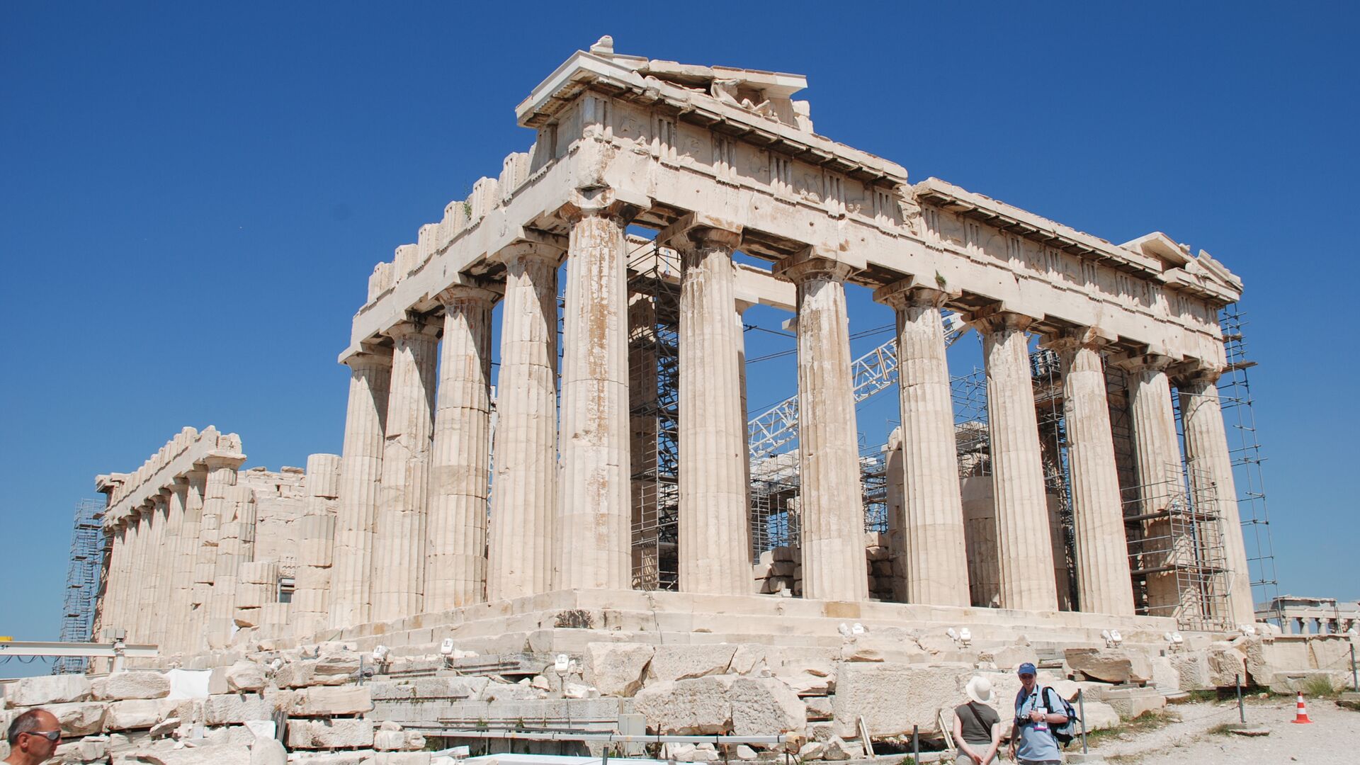 Two travellers gazing up at the towering pillars of a site at the Acropolis in Athens