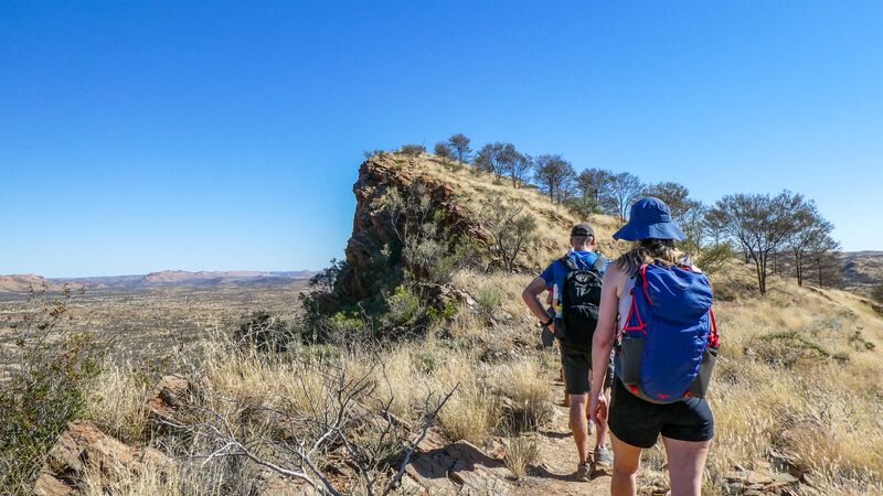 Two hikers walking the rugged terrain of the Larapinta Trail in the Northern Territory, Australia