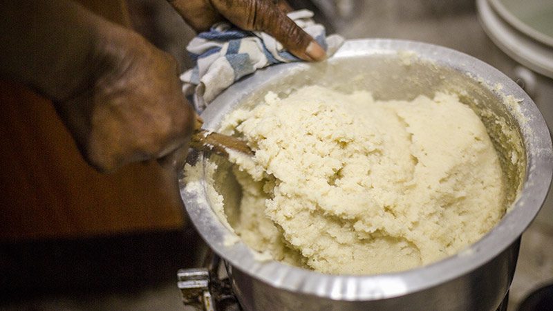 A man mixing a big bowl of ugali in Kenya. 