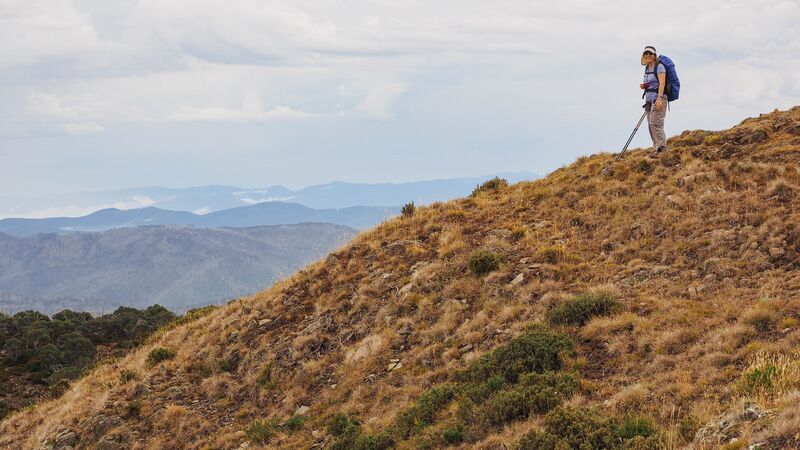 A lone hiker smiling at the camera on top of a hill along the Great Ocean Walk.