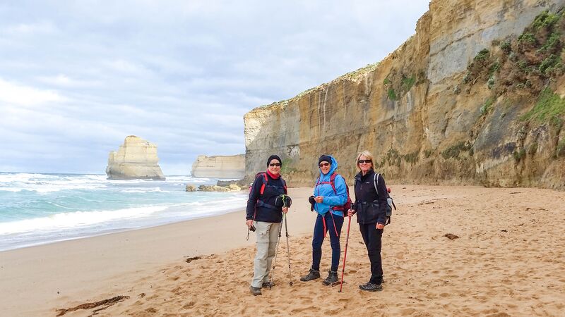 A few hikers facing the camera on a beach in Victoria.