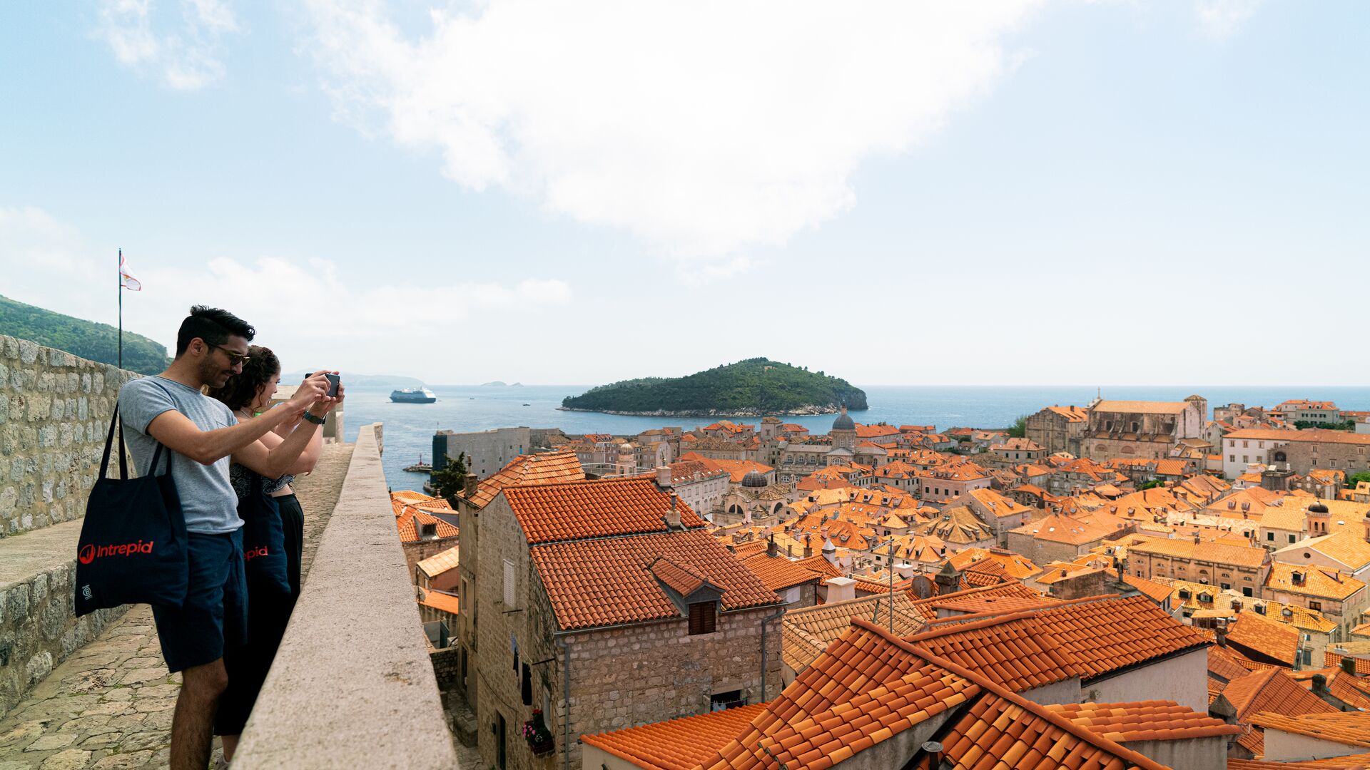 Two travellers look out over the red roofs of Dubrovnik, the city that stands in for Game of Thrones' Kings Landing. The sea is visible in the distance.