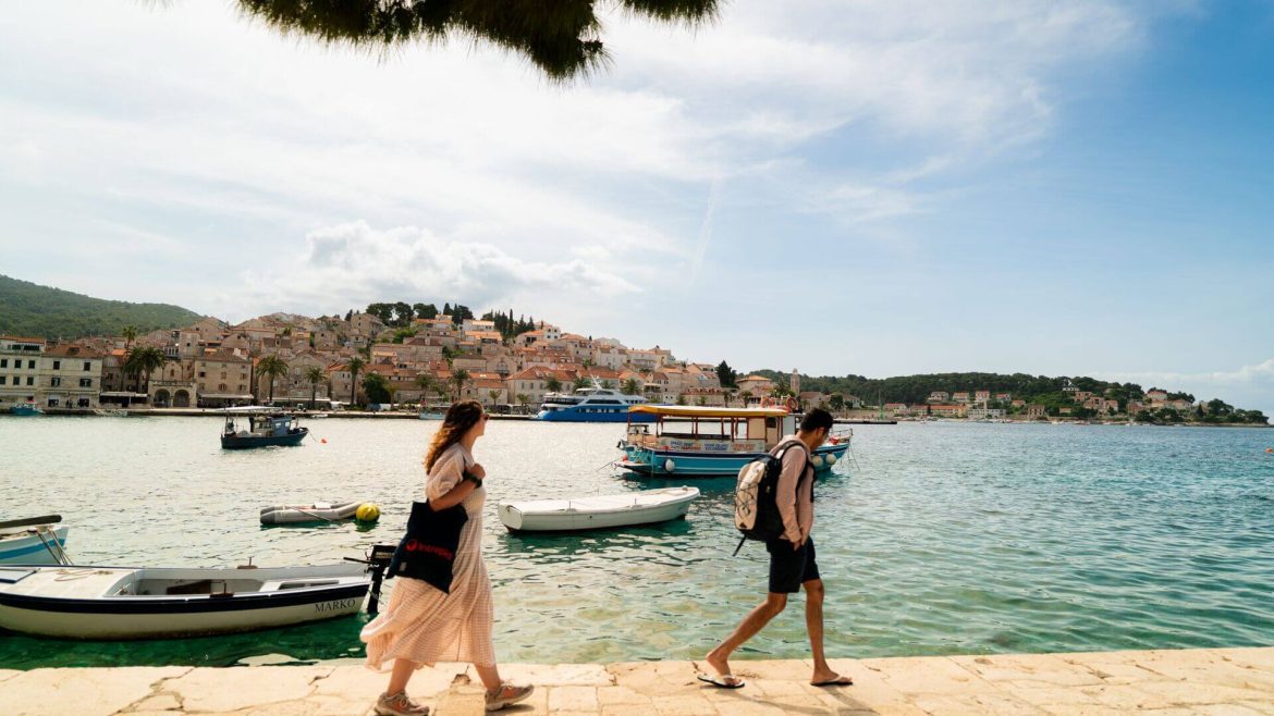 Two travellers walk by the water in Hvar, Croatia