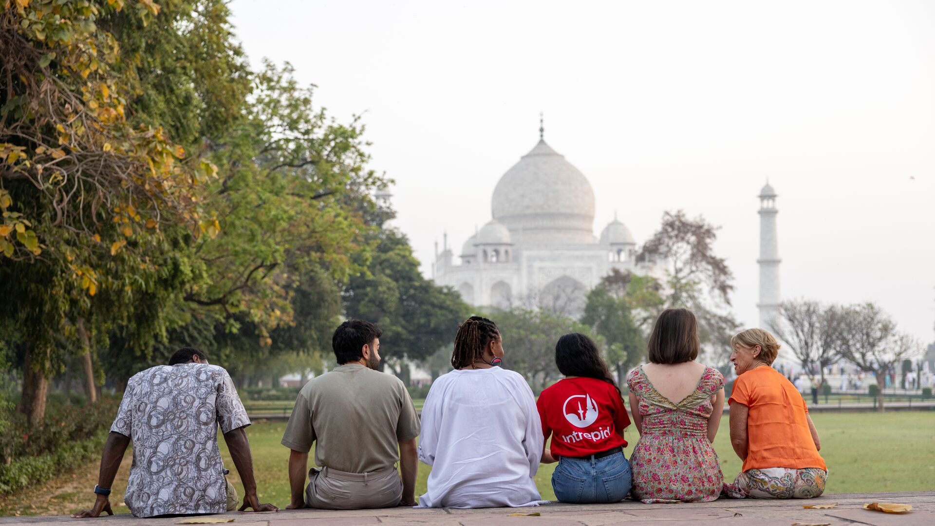 A group of Intrepid travellers and their leader admire the Taj Mahal from afar.