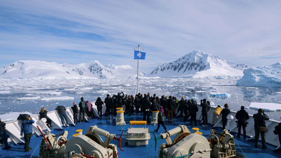 Antarctica boat travellers look out over the railing as the ship approaches Antarctica