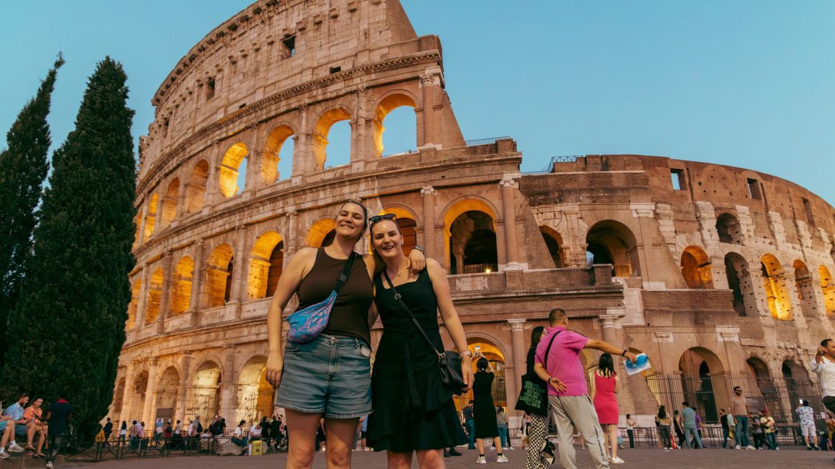 Two travellers posing outside The Colosseum in Rome, Italy