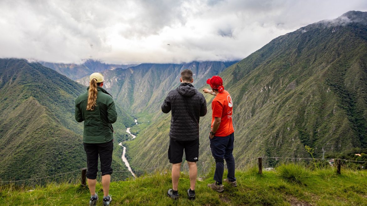 Two travbellers and an Intrepid leader looking out at the valley below a scenic ridge on the Inca Trail