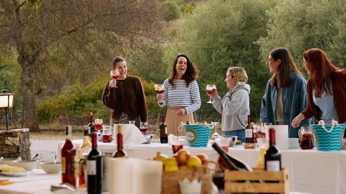 A group of 5 women holding glasses of Sangria laughing together