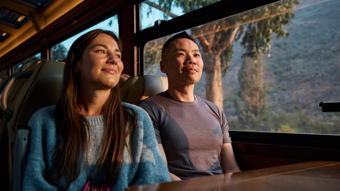 Two travellers watching the scenery roll past on the train to Aguas Calientes