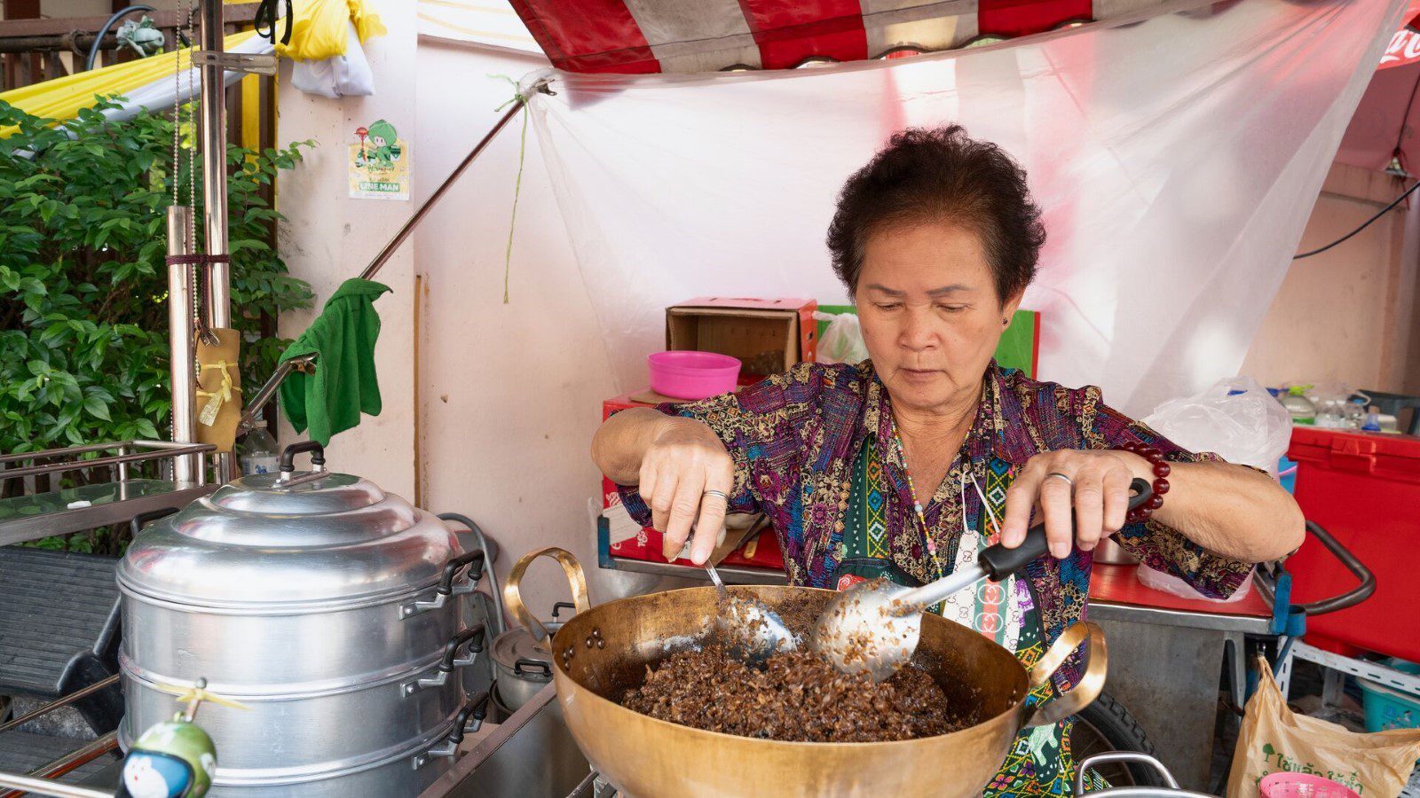 A local woman cooks something delicious looking at her food stall in Talad Noi, Bangkok