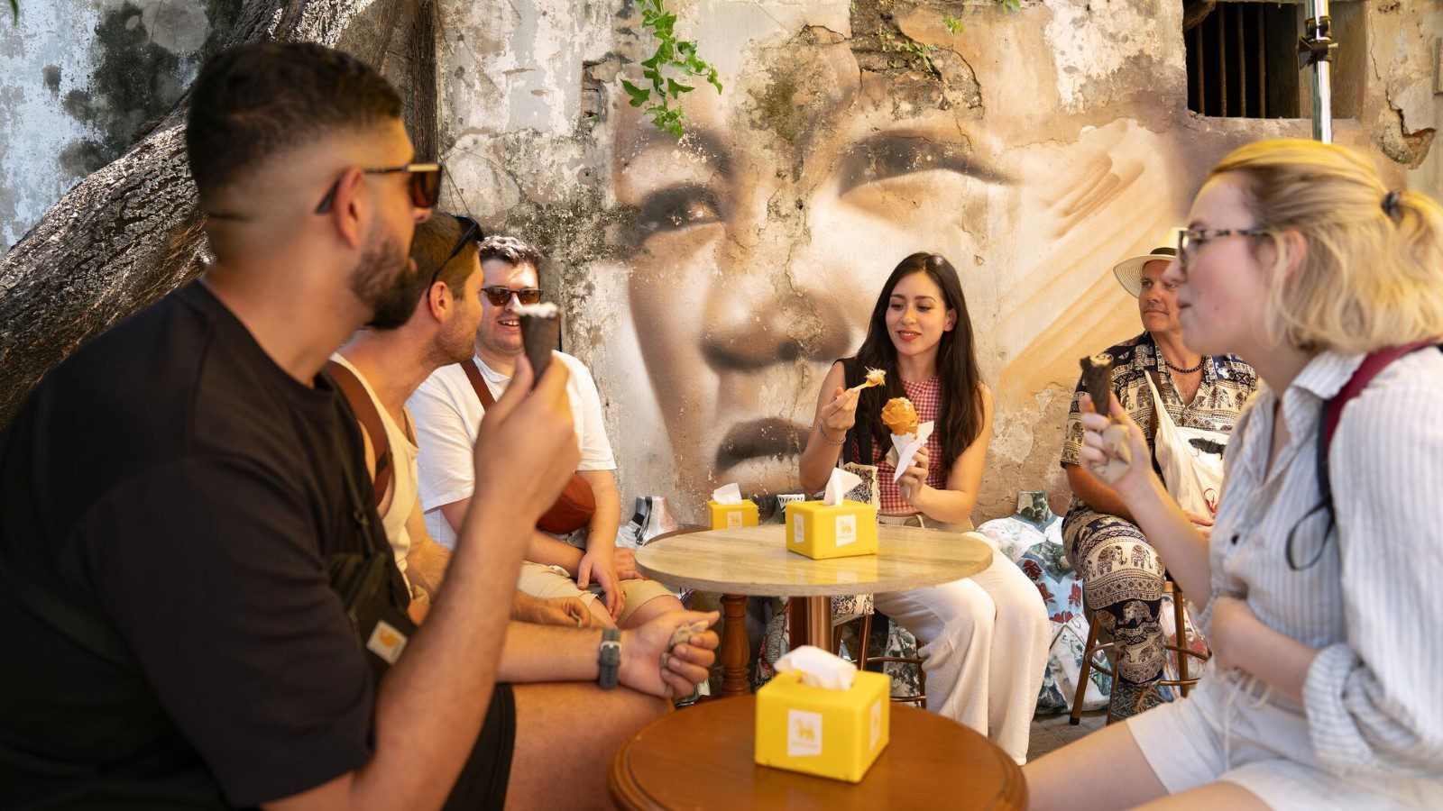 A group of travellers chat over ice creams at a cool Bangkok cafe.