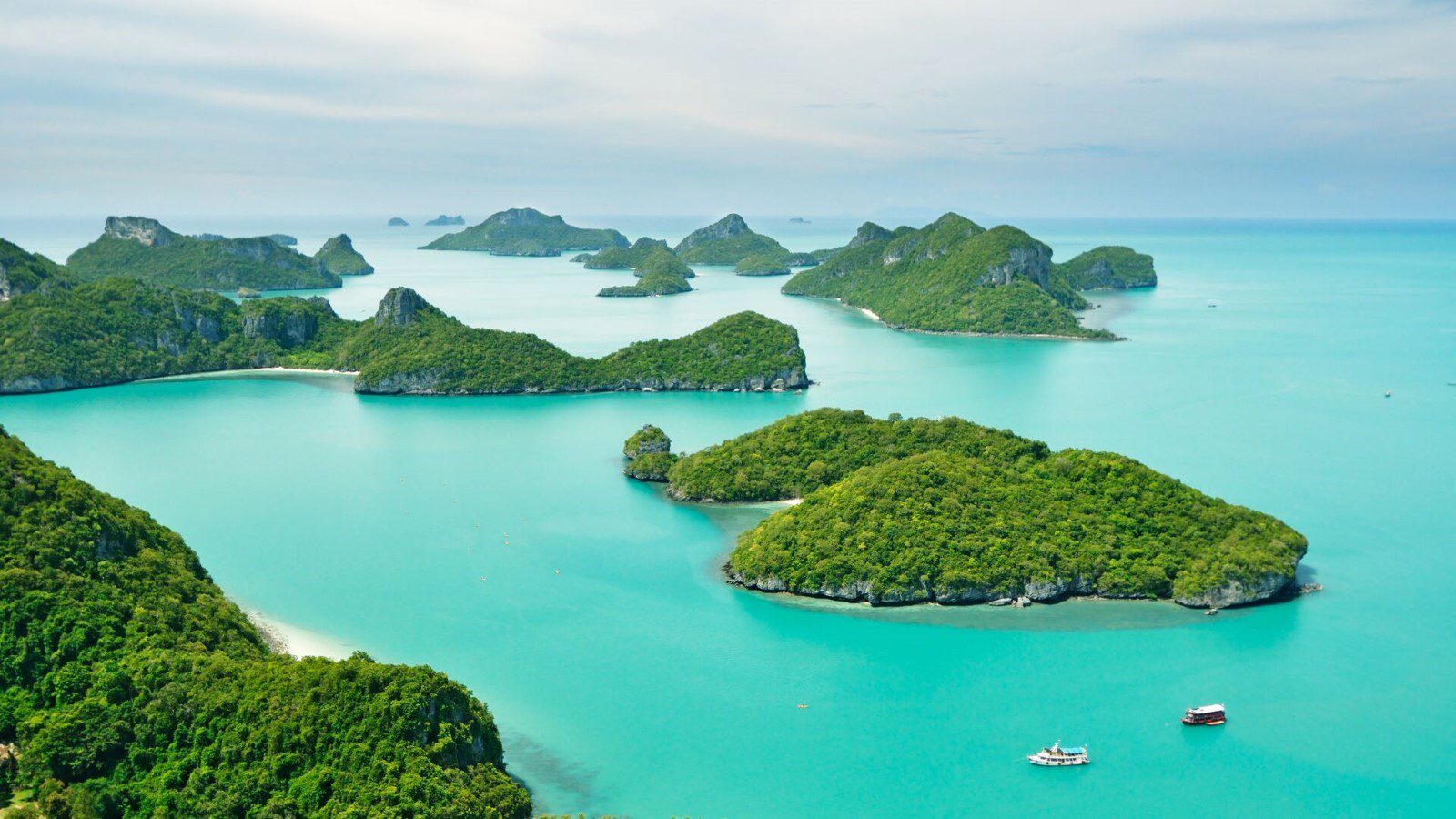 A classic view of Thailand's turquoise water and jungle-shrouded islands. Oh to be on that little boat on the way to a paradise beach.