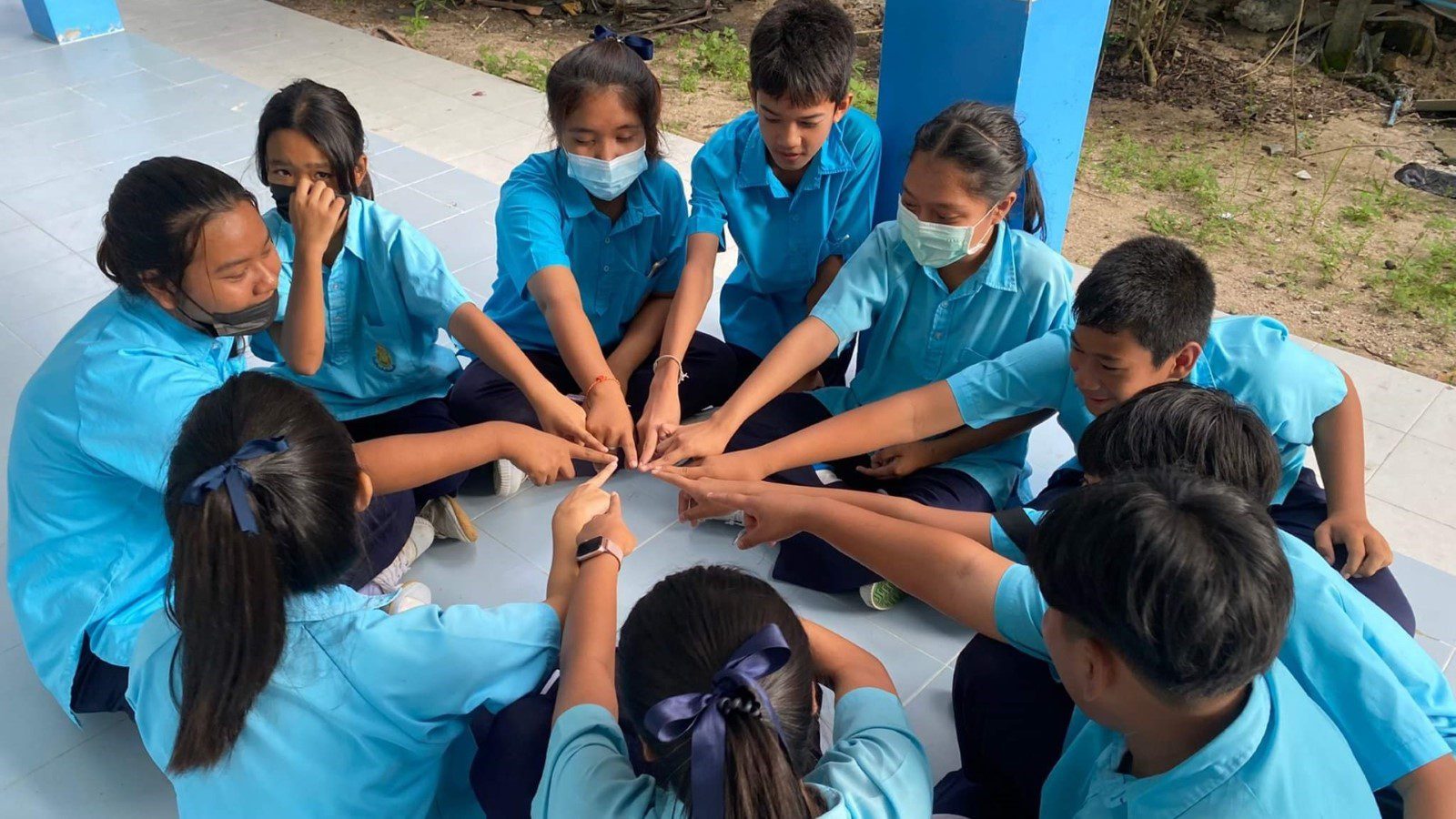 A group of kids and their teacher huddle in the classroom during an environmental education session