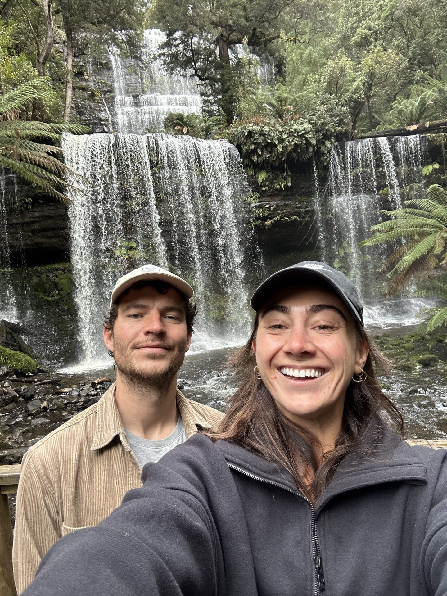 Cam and Gemma smiling by a waterfall in Tasmania