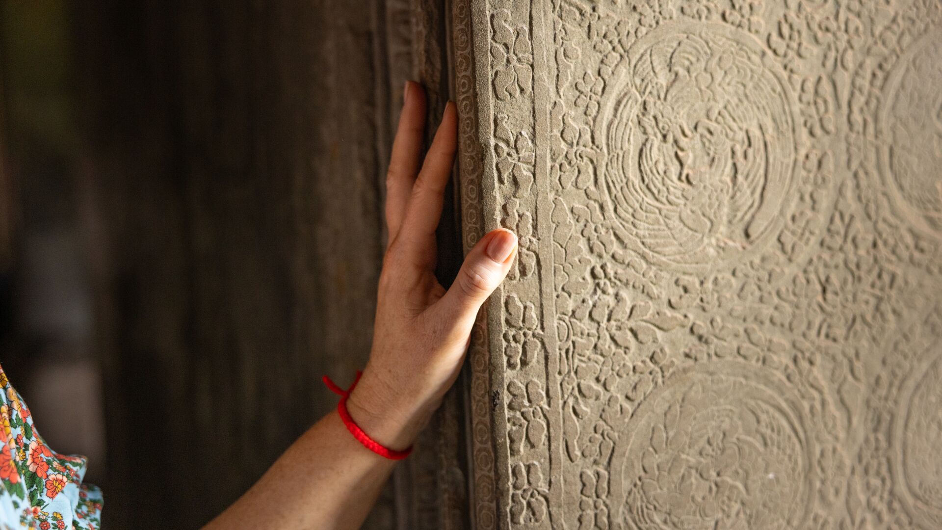A hand on the intricate stonework of Angkor Wat