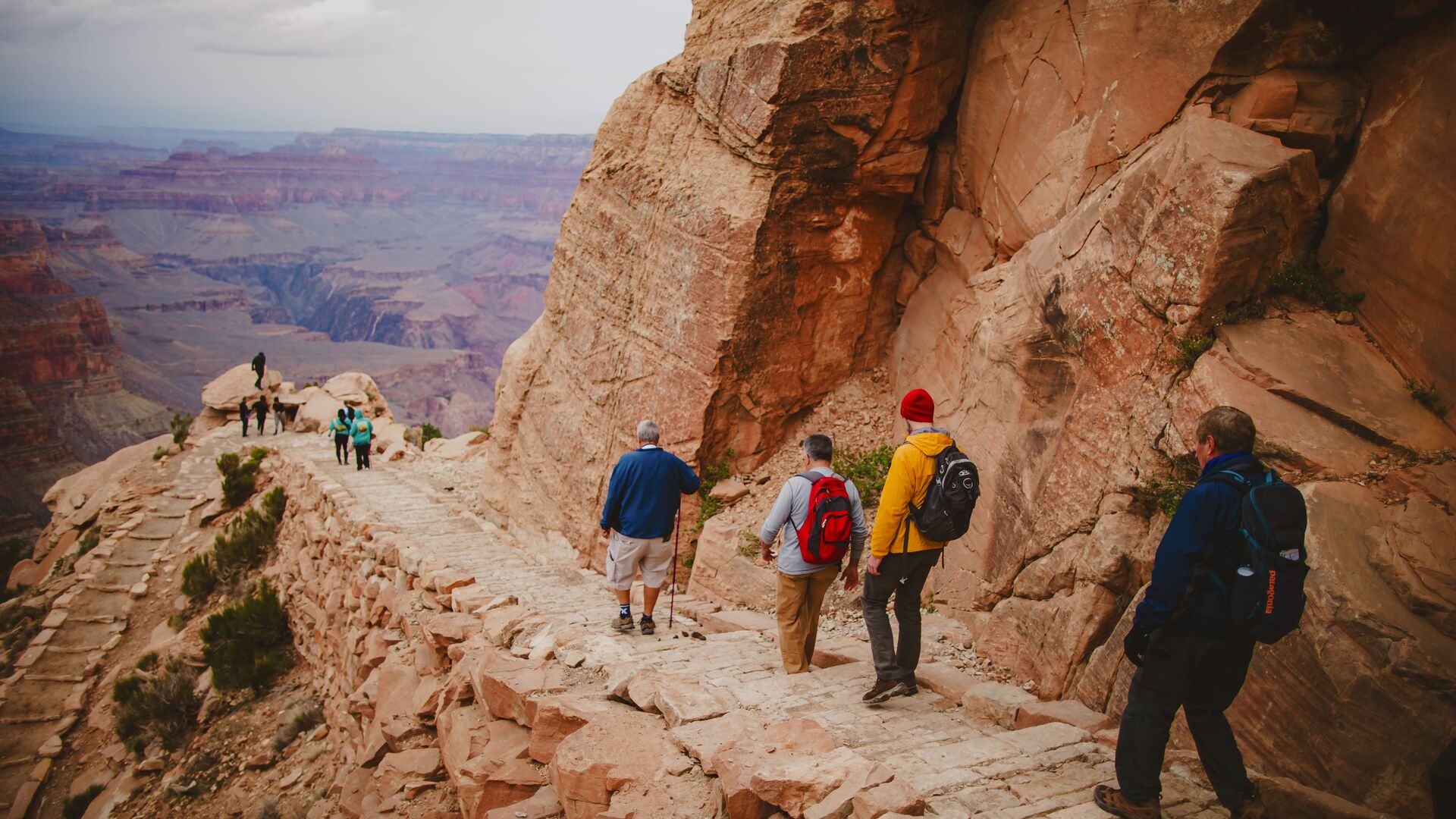 Hikers descend a rocky switchback path overlooking the Grand Canyon, USA