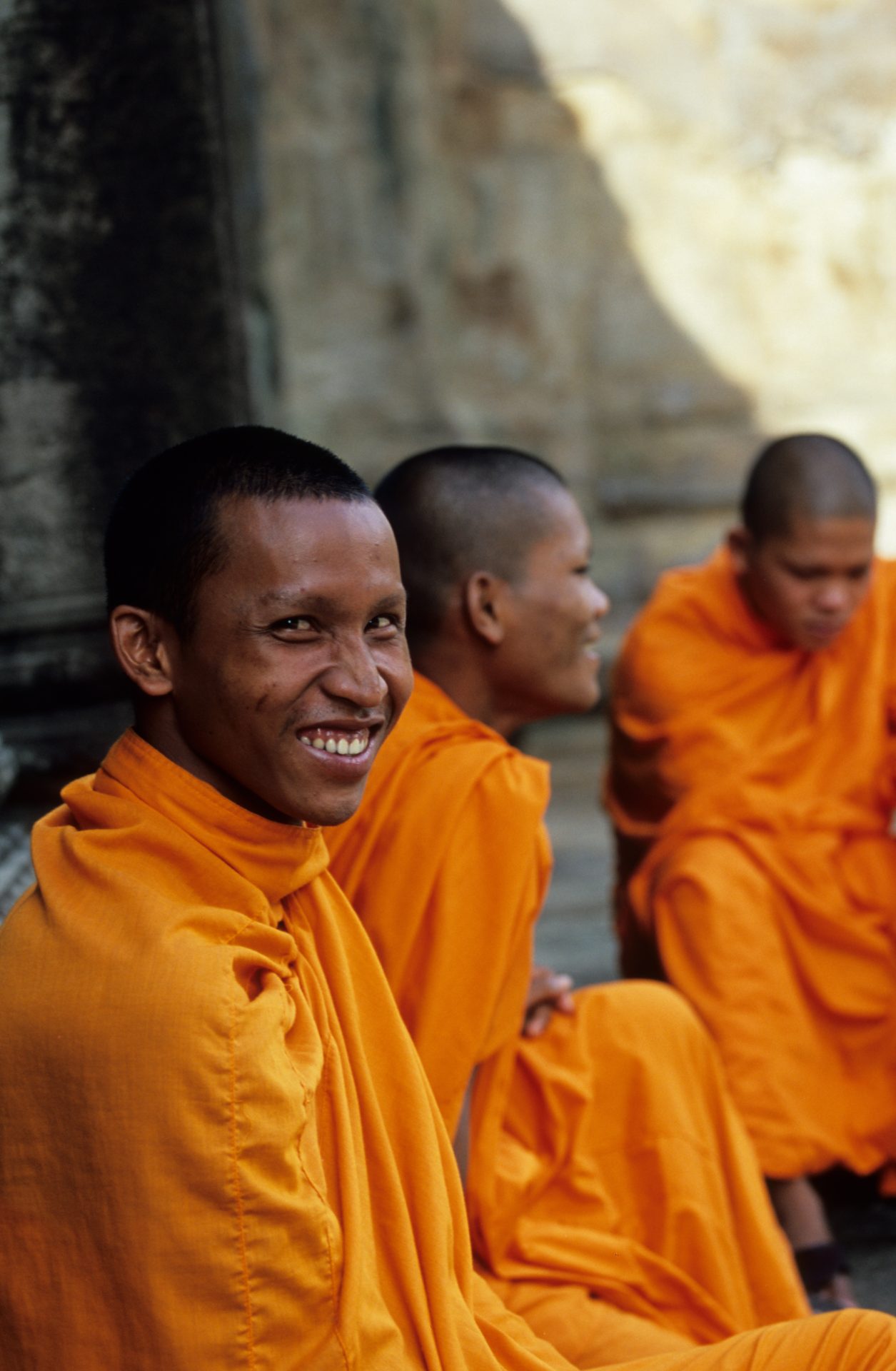 A monk in orange robes smiles at the camera