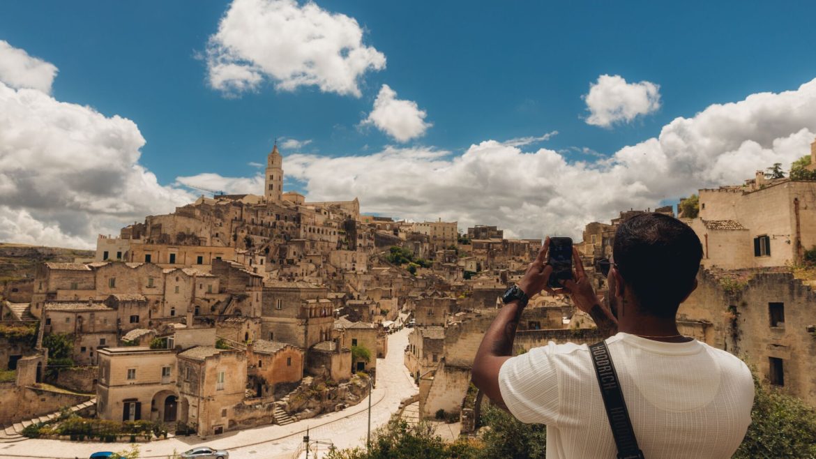 A traveller takes a photo of Matera's skyline under the sun