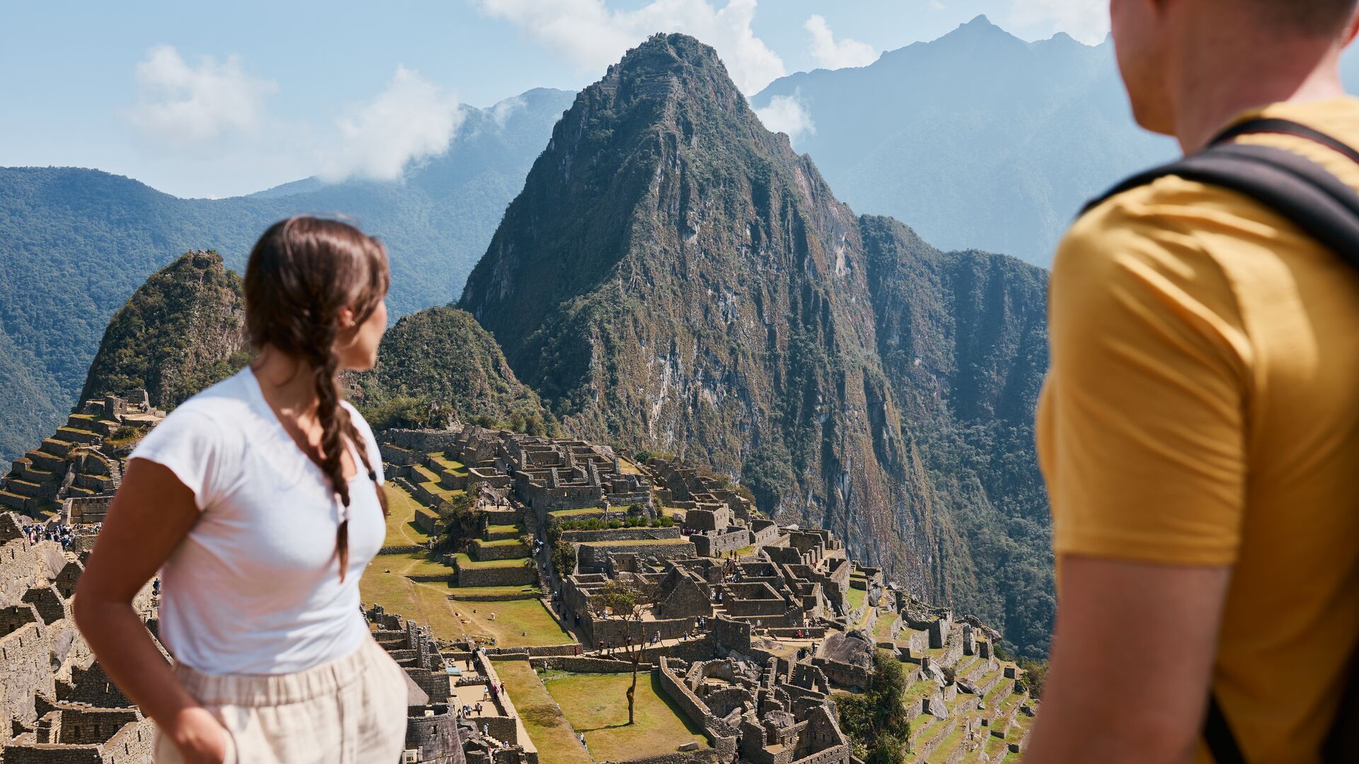 Two travellers admire the view of Machu Picchu from up high on the hillside in Peru
