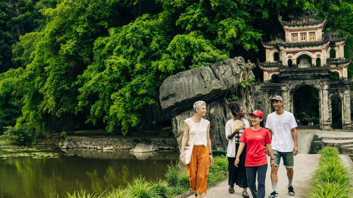 An Intrepid leader and three travellers walk in front of an ancient doorway in Vietnam